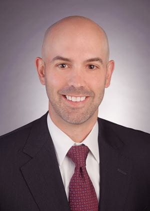 Head shot of Dr. Vincent DiNapoli wearing a black suit and red tie.